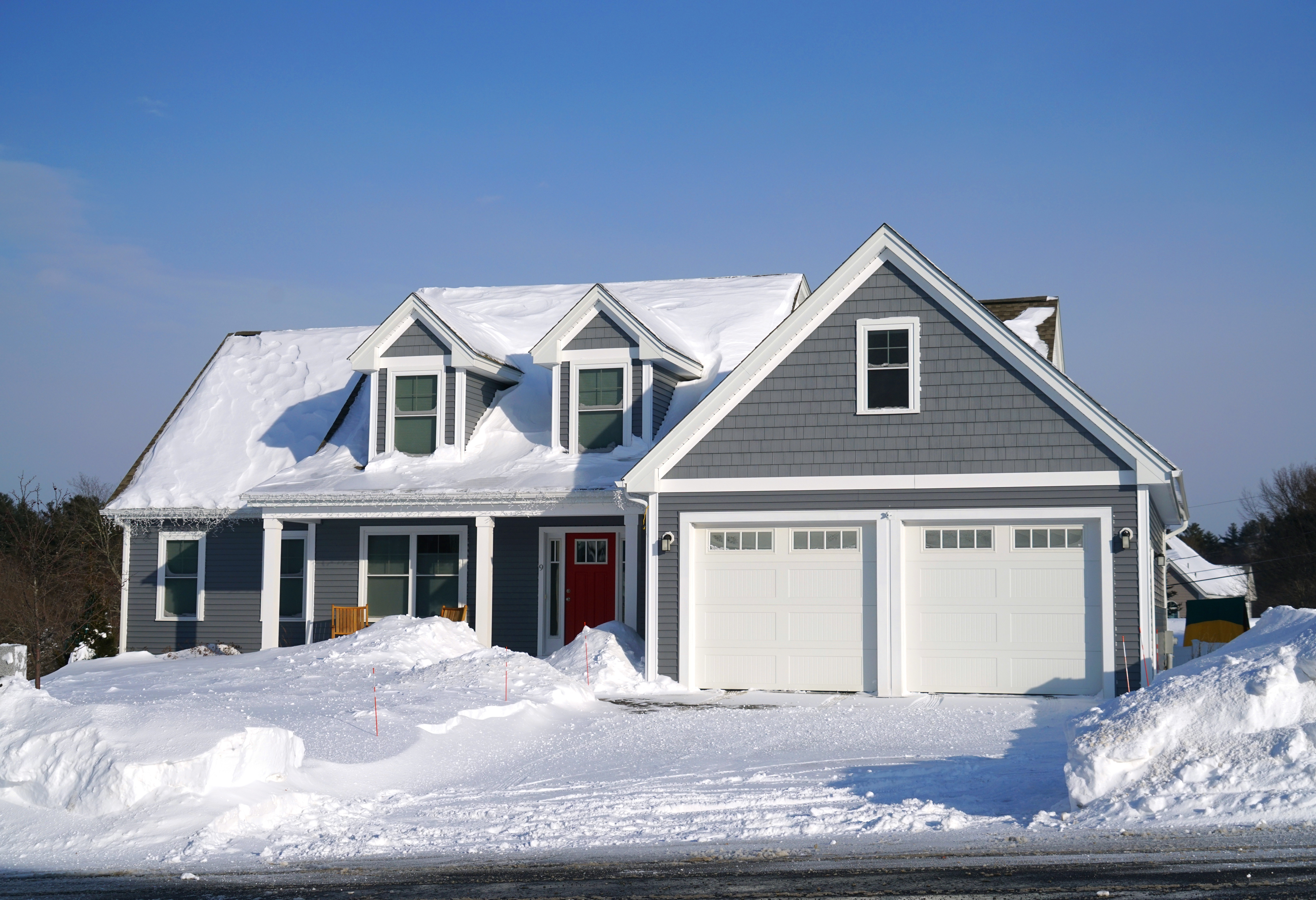 gray craftsman style home with snow on its roof and in the yard