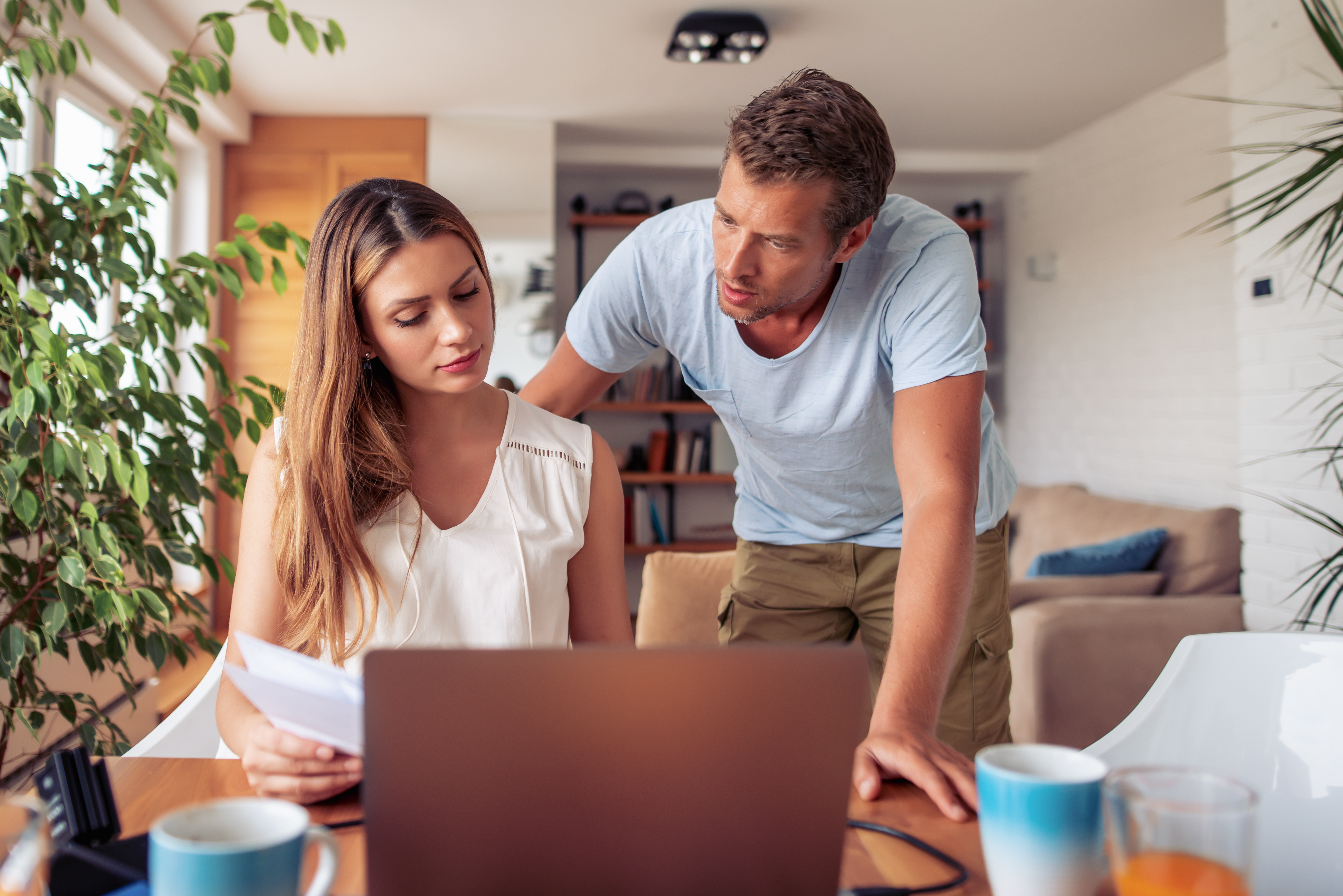 couple looking over paperwork deciding what to do in front of a laptop
