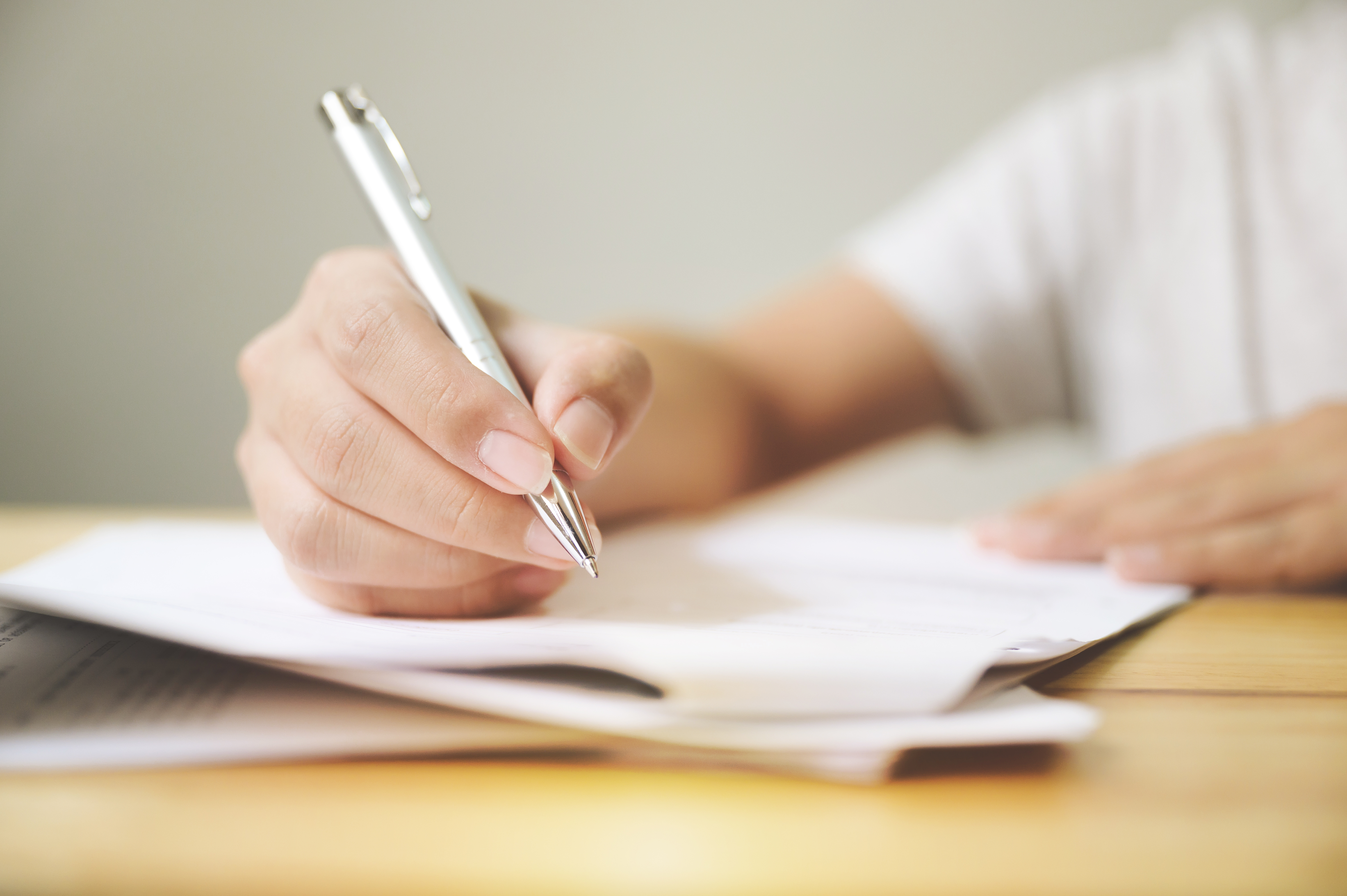 person filling out paperwork on a wood table