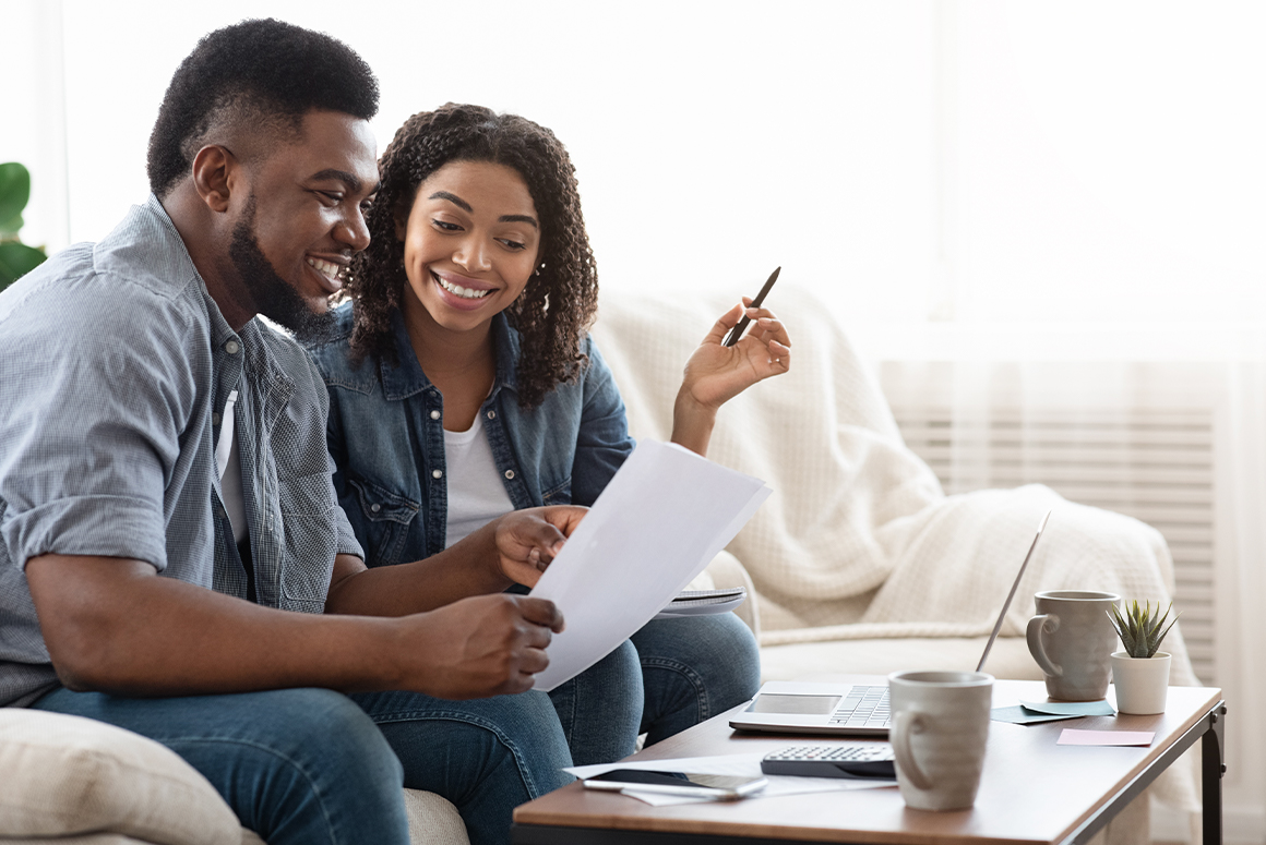 Black couple looking over paperwork on their couch