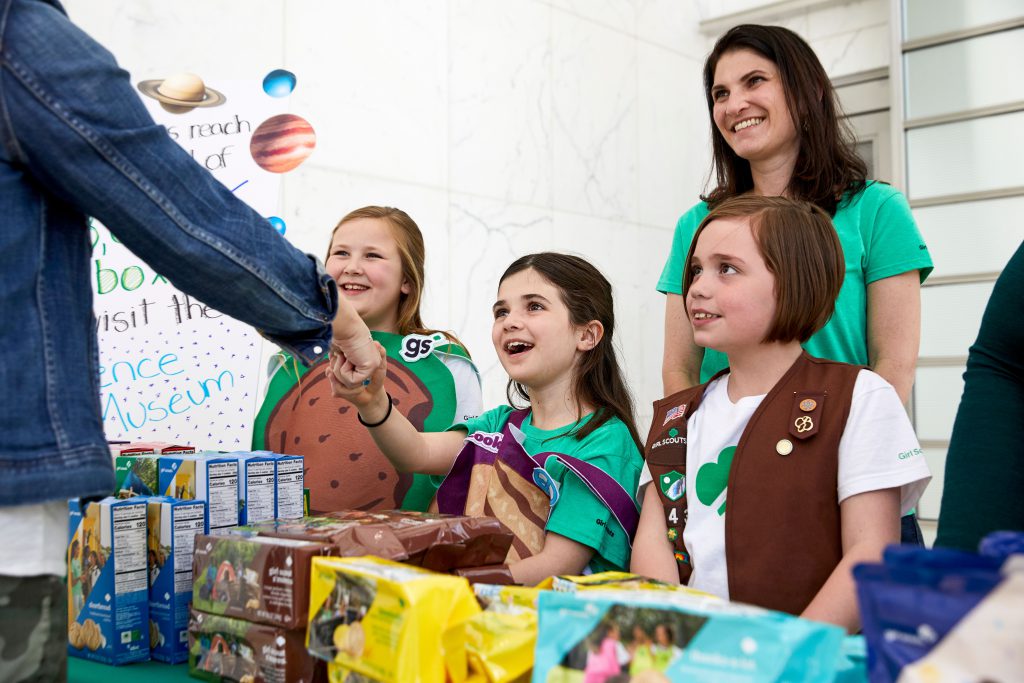 Girl Scouts shaking hands with a cookie buyer.