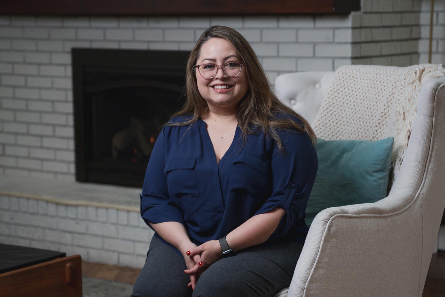 denise sitting in a living room, on a chair. She looks inviting and trustworthy.