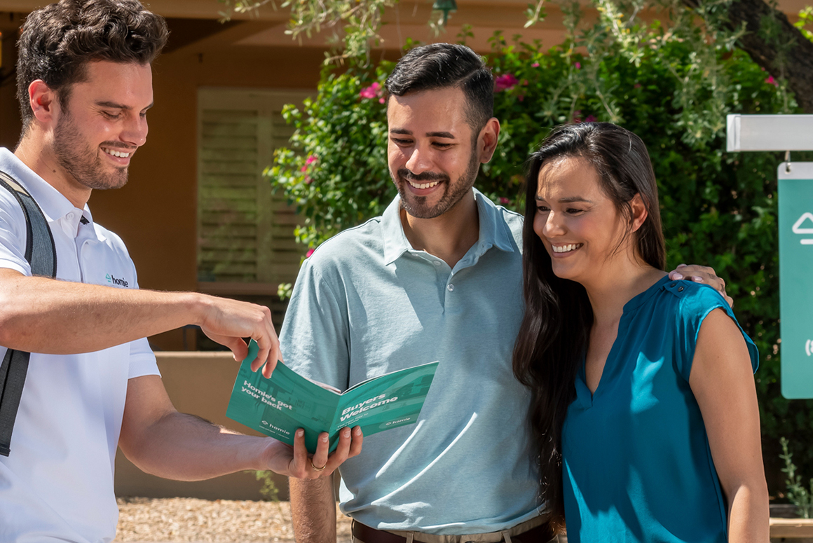 couple outside of home with Homie agent, looking over homie buyer information