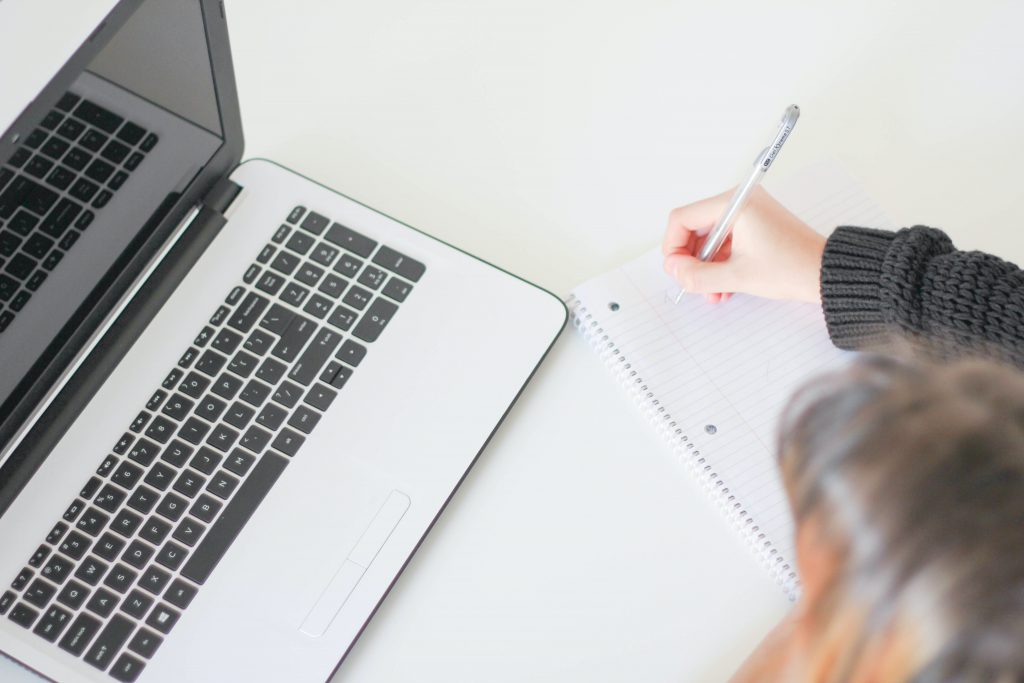 woman at a laptop, taking notes