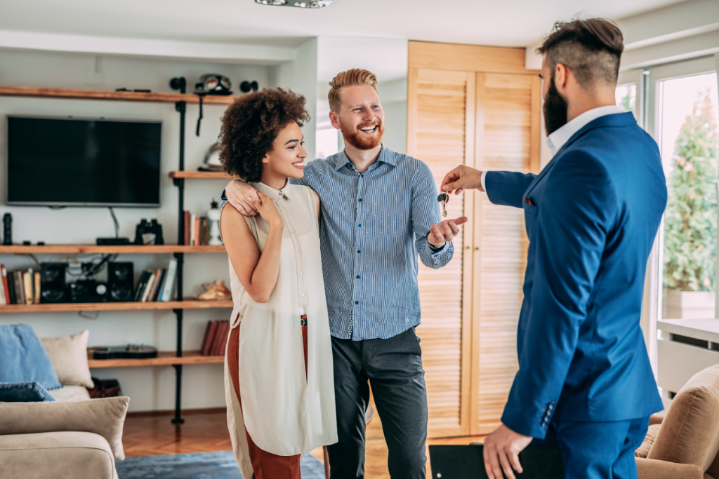 young couple receiving keys to their new home after a real estate transaction