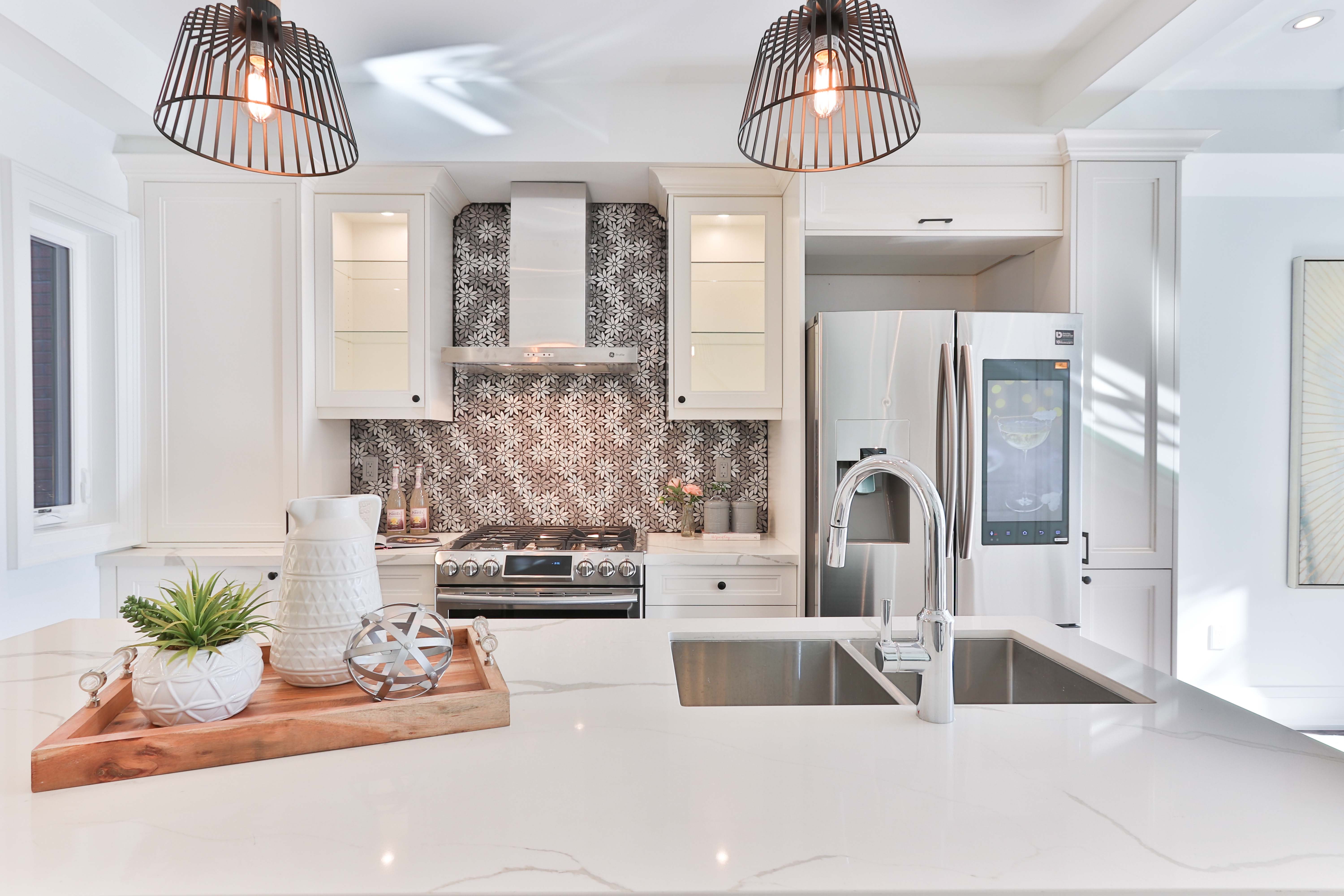 white kitchen with gray backsplash and a live plant on the countertop